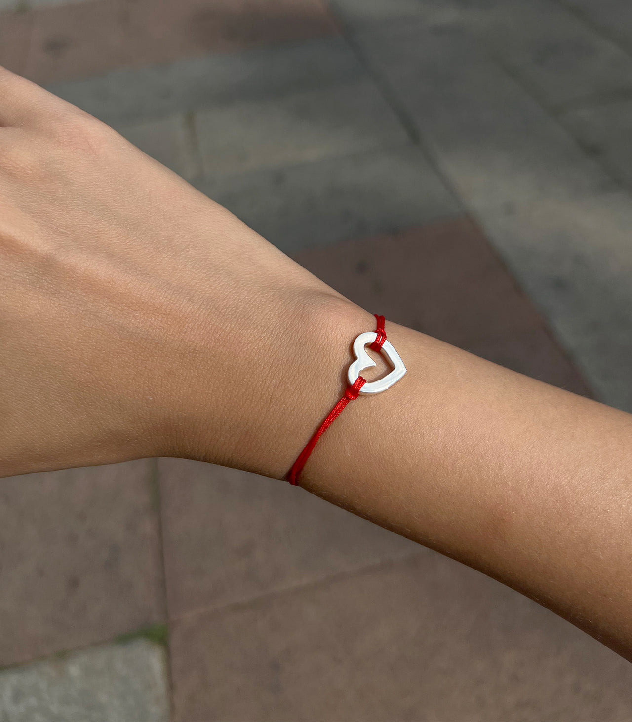 pulsera corazón de plata en hilo rojo puesta
